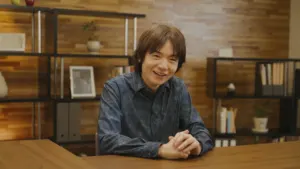 Masahiro Sakurai smiling at a desk during an official Nintendo presentation
